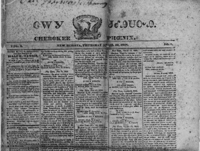 Newspaper print with 4 columns of tiny print. Title is Cherokee Phoenix in English with Cherokee symbols on top.