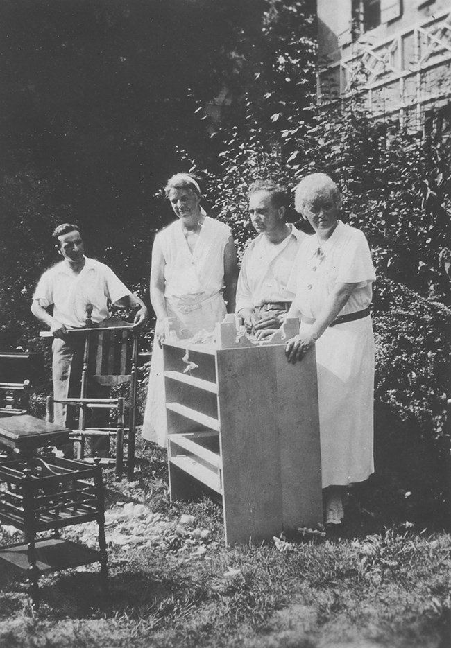 Two women and two men outside a building surrounded by furniture.
