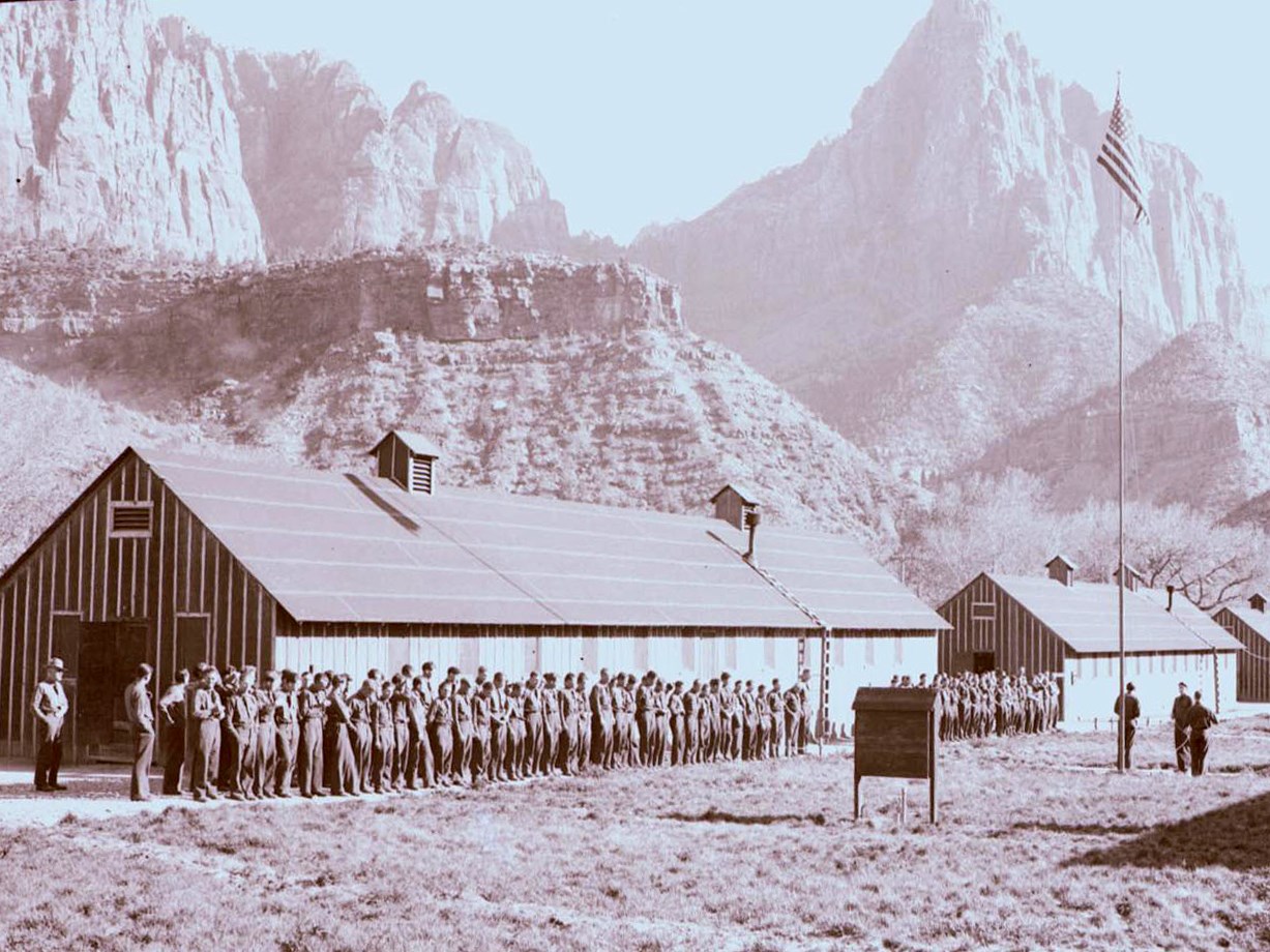 Group of men standing by a flag pole.