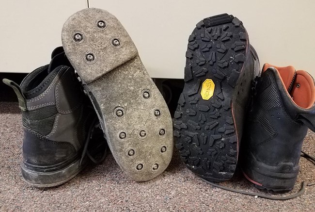 Two pairs of wading boots are seen side by side. One has felt soles and one has rubber soles.