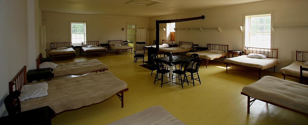 Hospital ward room with yellow wood floors and hospital beds.