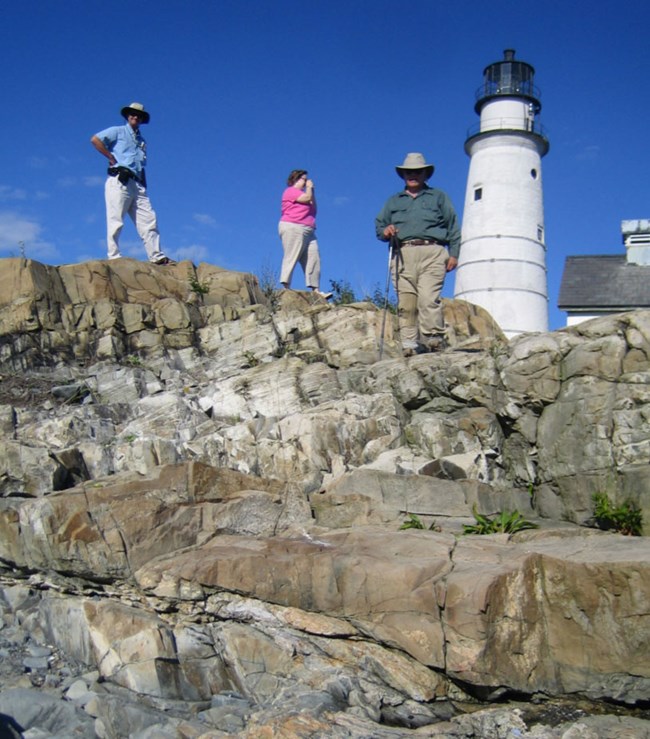visitors and lighthouse on rocky bluff