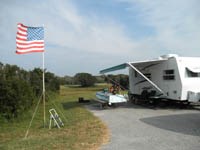 Campsite with RV, picnic table, chairs and American flag, 33kb.
