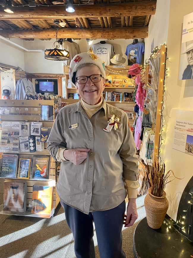Cheryl smiling at the camera in her tan volunteer uniform in the park's bookstore.