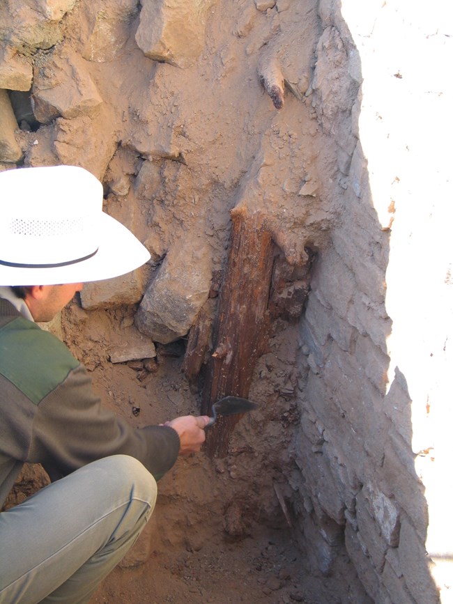 An archaeologist studying wooden beams at Aztec Ruins.