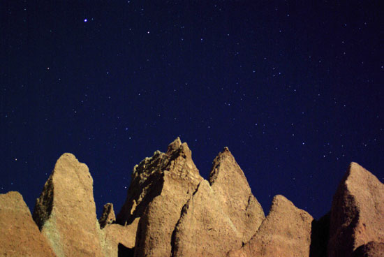 Badlands formations against the night sky with stars. 