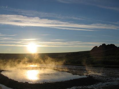 Steam rising from Serpentine Hot Spring at Sunset with tors in the background.
