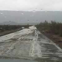 Water runs across the Old Maverick Road after a rain