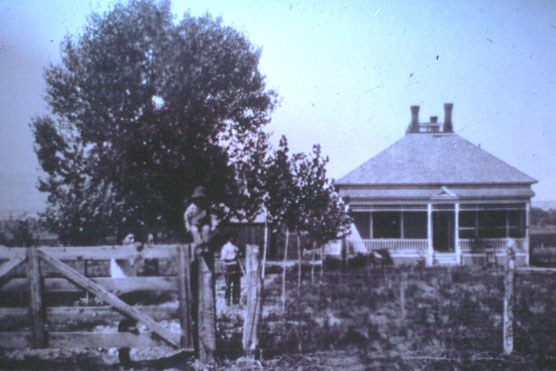 A child sits on the gate in this historic photo of Henry Clay Lovell's home on the ML ranch