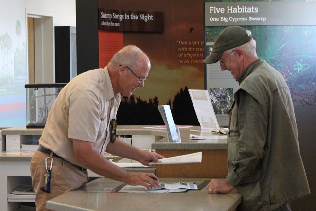 A volunteer helps a visitor at the main visitor center desk