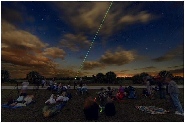 A ranger points out celestial objects with a green laser to onlooking visitors.