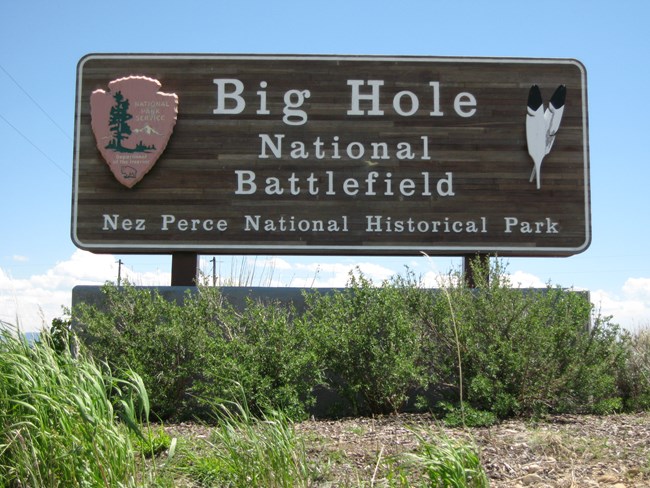 A wooden sign with the words "Big Hole National Battlefield Nez Perce National Historic Park" carved onto it.