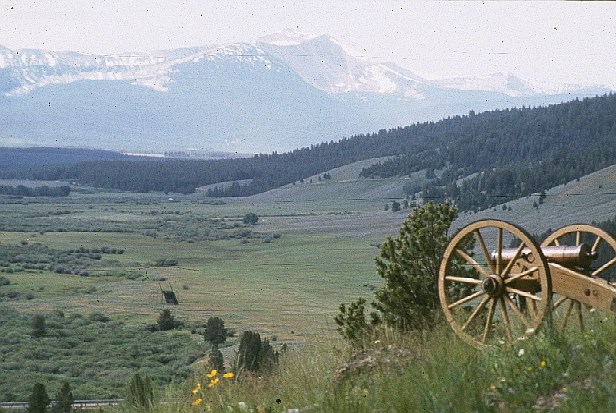 A mountain howitzer on hill overlooking a valley and the mountains.