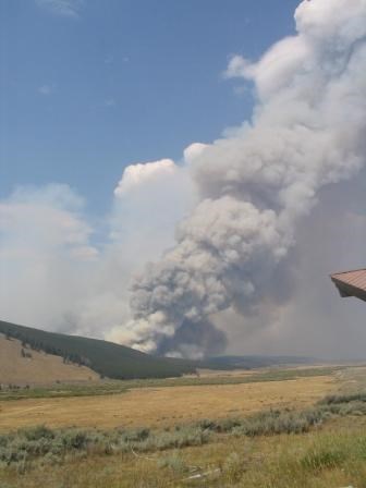 A field with a plume of smoke in the distance.