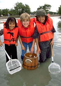 Three young girls share dipnets and a glass bottom bucket to explore the seagrass communities in the shallows of Biscayne Bay off of Elliott Key