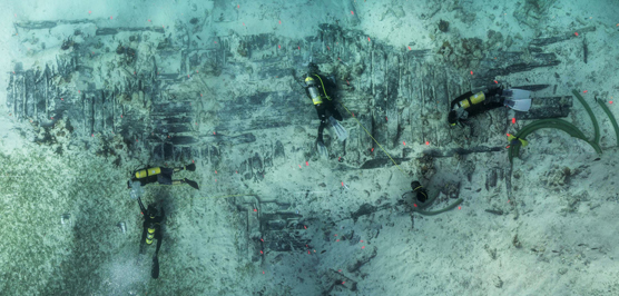 Divers float over the exposed timbers of the wreck of HMS Fowey.