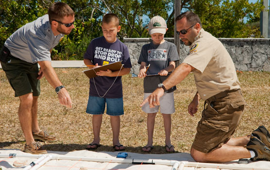 Two staffmembers assist two young boys interpret a shipwreck map at Family Fun Fest.