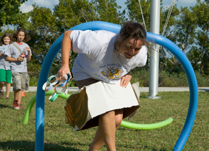 A participant in Family Fun Fest races through an abstacle course wearing a hermit crab shell.