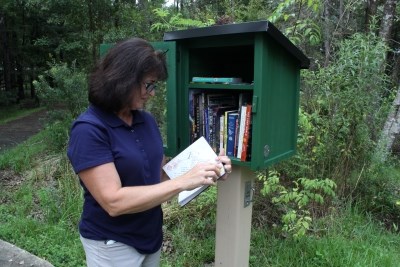 woman reading a book from little free library