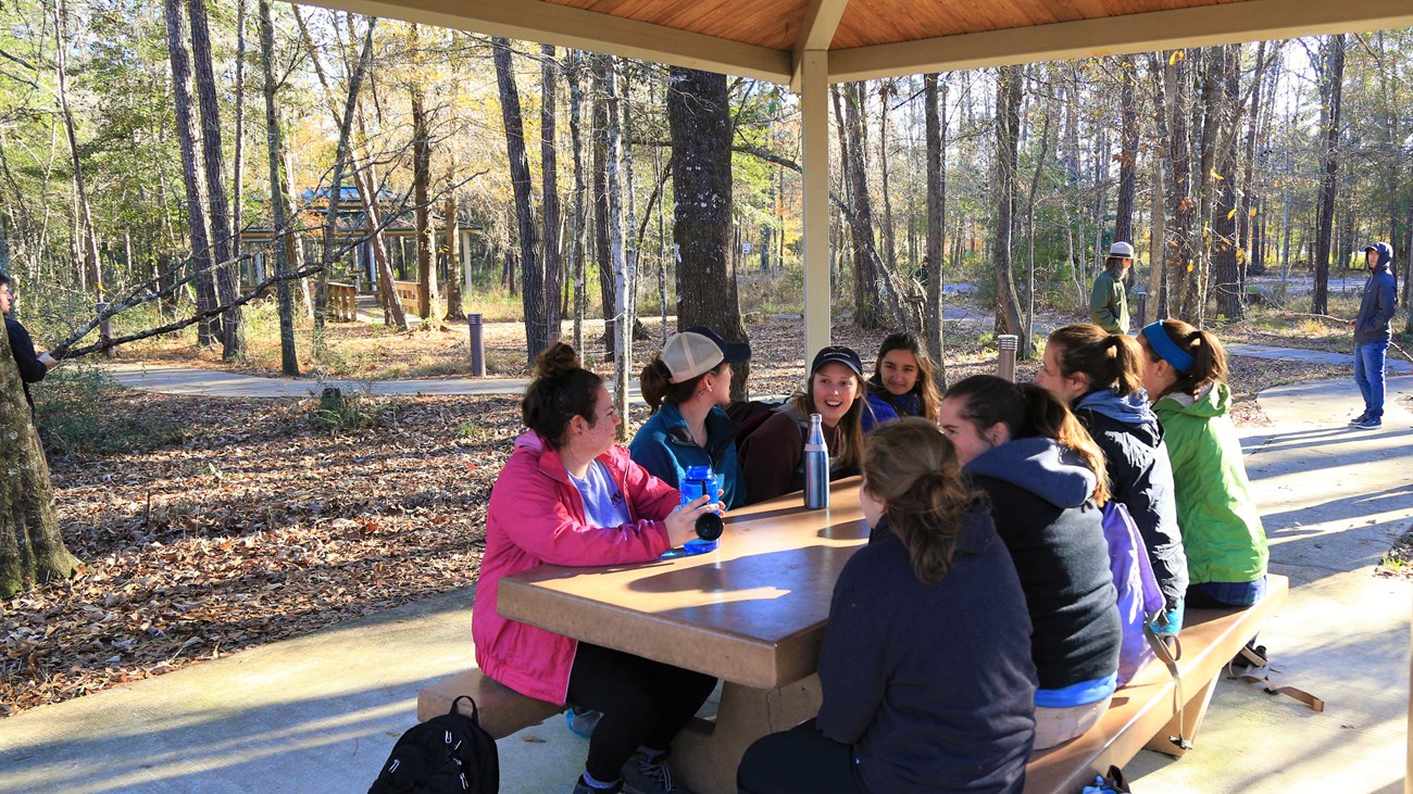 group of people sitting a picnic table in the visitor center's picnic area