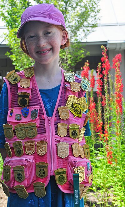A girl wearing a vest with dozens of junior ranger badges pinned to it