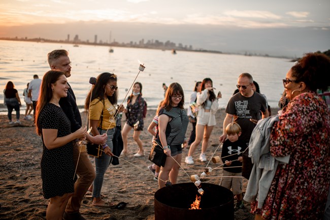 People roasting marshmallows on a beach bonfire