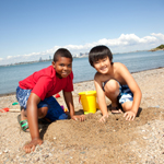Boys begin building a sand castle on Spectacle Island. 