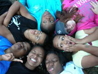 Green Corps lyouth laying down in a circle with their heads touching. 