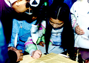 Kids signing a document with a quill pen