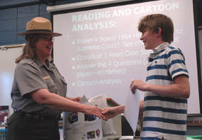 Contest winner David Spivak is congratulated by Tallgrass Prairie National Preserve Superintendent Wendy Lauritzen during class at Mission Valley Middle School.