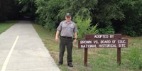 Ranger Randy stands next to the Landon Trail at a sign recognizing our adoption of a section of the trail for cleanup.