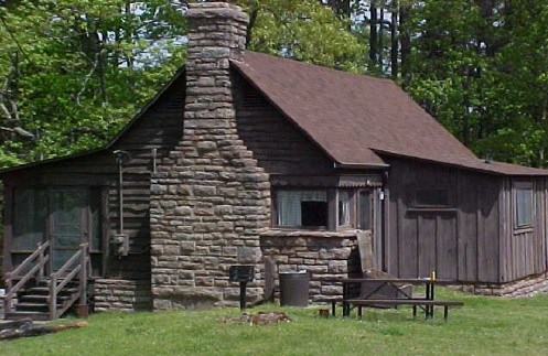 photo of brown cabin with stone chimney and board and batten siding
