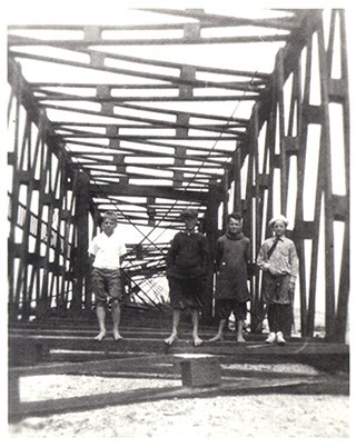 Four young boys stand inside a fallen square shaped metal frame radio tower.