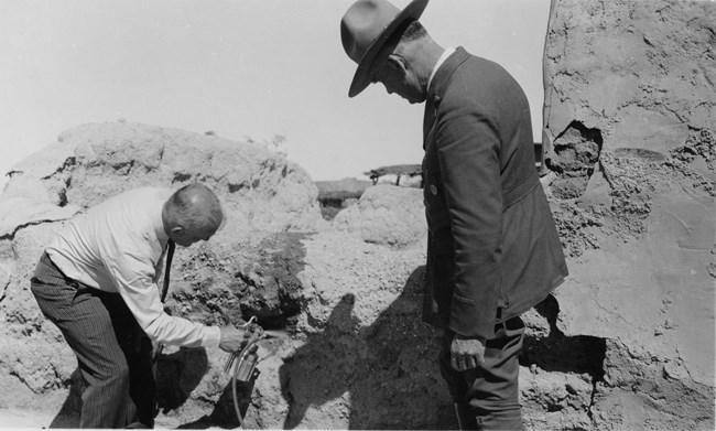 Black and white photographs from 1936 of man in dress pants and shirt spraying chemicals on ruins while uniformed ranger watches