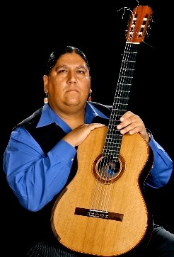 Gabriel Ayala sits with his guitar in this studio photograph