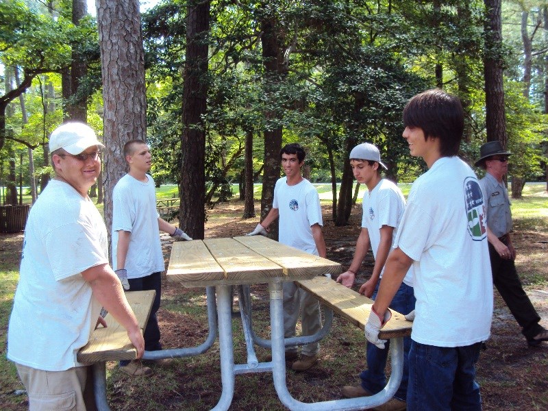 Members of the park's Youth Conservation Corps crew work on a picnic table.