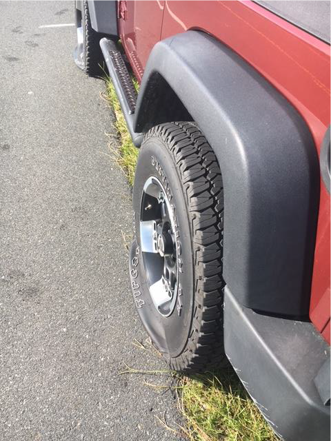 Slashed rear tire on a red Jeep Wrangler.