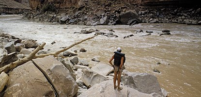 a man in a life vest stands on a rock on the edge of a river