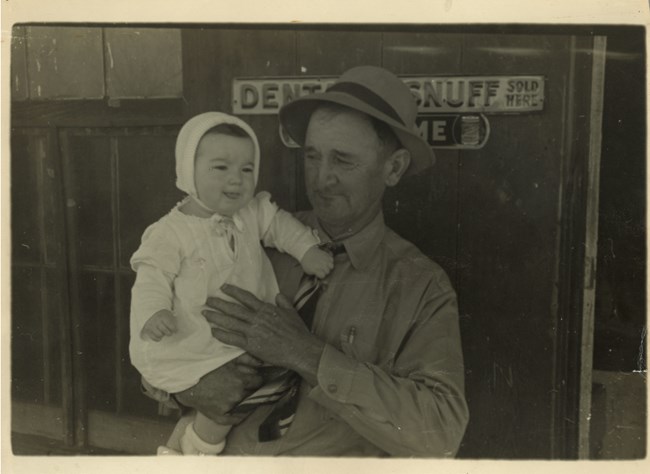 A man stands holding a baby.