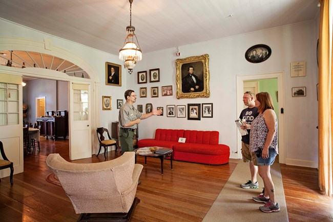 Ranger Rodney Meziere talks with visitors in the parlor of the Oakland Main House