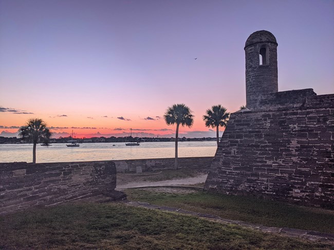 Sunrise with purple and pink hues over as seen from the north lawn of the Castillo and Matanzas River.