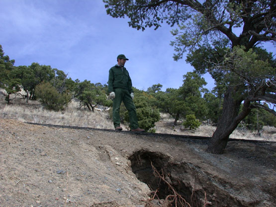 color photograph of park service staff examining eroding gully by volcano road