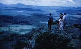 Color photograph of view from rim trail with ranger and visitors on trail.