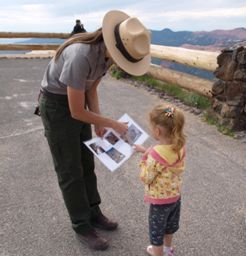 A ranger helps a young visitor become a Junior Ranger.