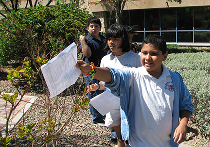 A trio of students hold a worksheet during a scavenger activity.