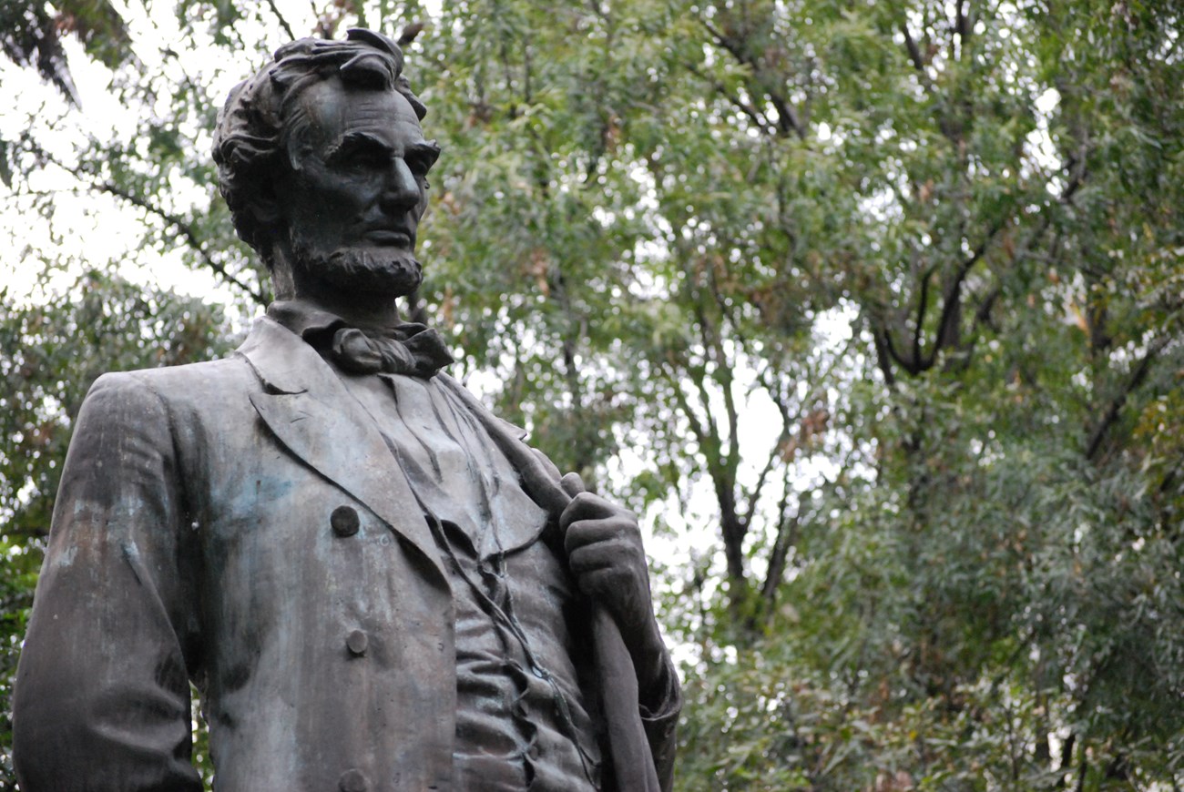 Head and torso of bronze statue of Abraham Lincoln with left hand clutching the lapel of his coat