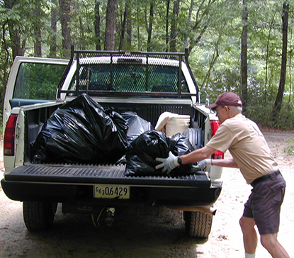 A volunteer loads bags of trash into a pickup.