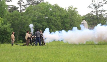 Living historians in Confederate uniforms fire a cannon at Chickamauga Battlefield