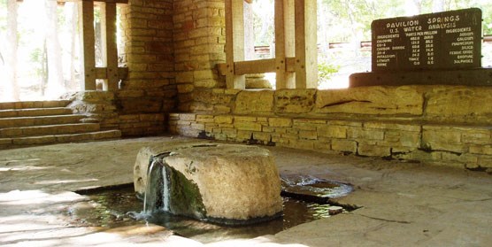 Interior of stone spring pavilion with water coming out of a large boulder