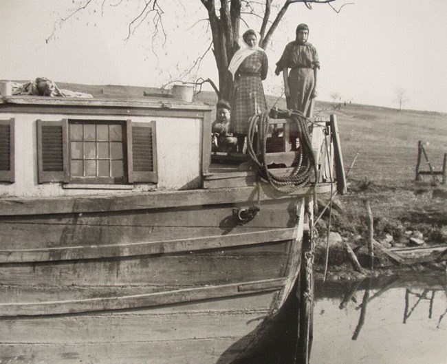 Black and white photograph of three women working on a canal boat.
